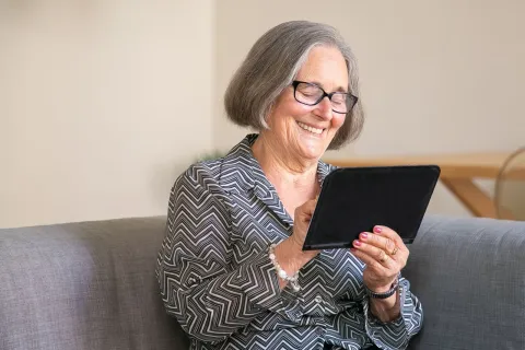 Femme senior souriante consultant une tablette numérique à son domicile